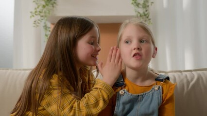 Two caucasian kids girls children sisters friends playing together at home older sister telling little girl news whispering in ear speak in whisper sharing secret gossip family relationship friendship - Powered by Adobe