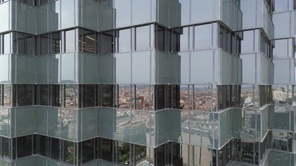 Bottom view of office building window close up, reflection and perspective. Modern architecture with sun ray. Glass facade on a bright sunny day with sunbeams on the blue sky.