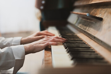 female hands playing the old vintage piano with white keys