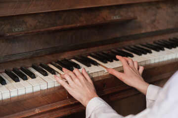 female hands playing the old vintage piano with white keys