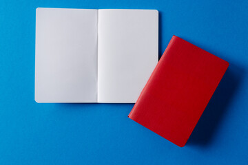 Close up of red notebook and open book with copy space on blue background