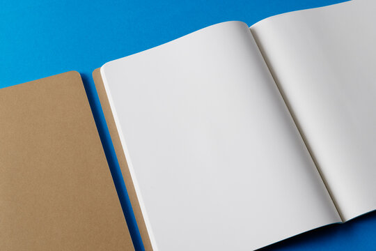 Close up of beige notebook and open book with copy space on blue background