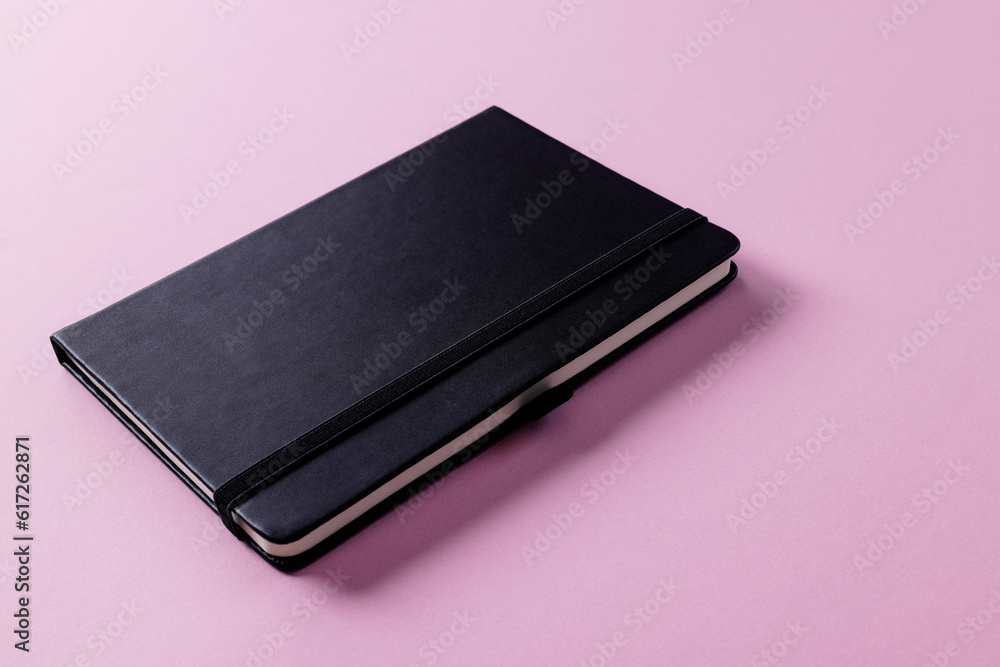 Poster close up of black notebook with copy space on pink background