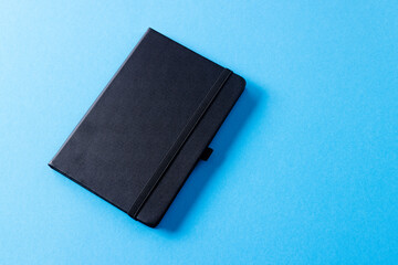 Close up of black notebook with copy space on blue background