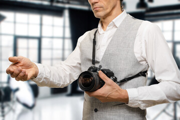Professional male photographer earning money taking photo in modern studio. exuding confidence and expertise as he holds out his hand, signaling his readiness to receive payment for his laborious