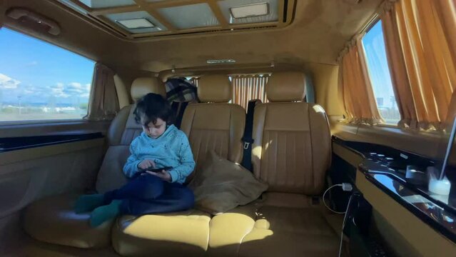 Boy travels in a luxury transfer. Child in car holds a smartphone in his hands