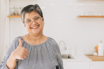 portrait happy healthy mature asian woman smiling cute lovely at home kitchen hand thumbs up