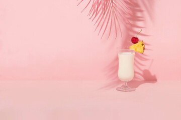 Summer creative layout with cocktail glass with cherry and pineapple slice and pink palm leaf on pastel pink background. 80s or 90s retro aesthetic idea. Minimal summer drink idea.