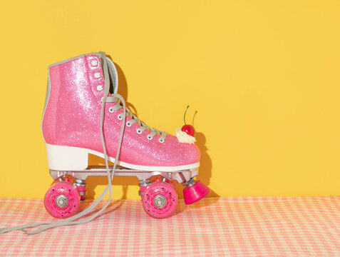 Summer creative layout with pink roller skate with whipped cream and bright red cherry on pastel pink plaid and yellow background. 80s or 90s retro aesthetic idea. Minimal summer fashion girl idea.