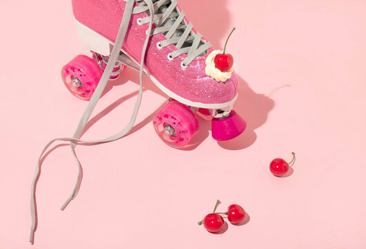 Summer creative layout with pink roller skates with whipped cream and bright red cherries bright red cherries on pastel pink background. 80s or 90s retro aesthetic girl idea. 