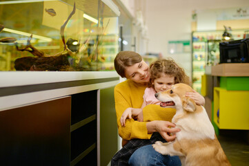 Happy family at pet shop with their loving corgi dog