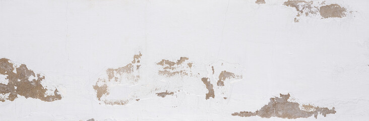 Old white wall with peeling plaster, grunge background