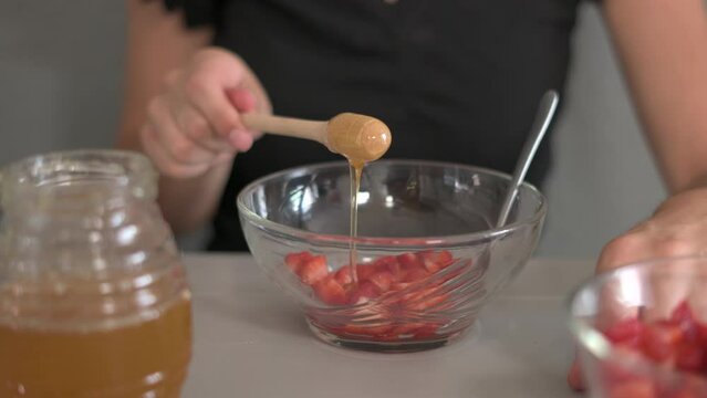 woman serving strawberries with honey in a glass bowl. healthy food concept