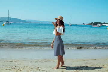 young woman on the beach with the phone sending a voice or audio message