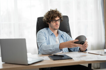 Caucasian businessman working with notebook computer and looking product example at office