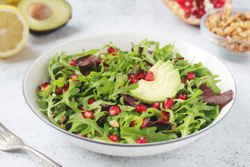 A plate with green rocket salad with pomegranate and avocado