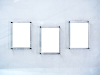 Three mockups of white blank paper poster or photo frames, acrylic materials, vertical style hanging on white dirty wall background.