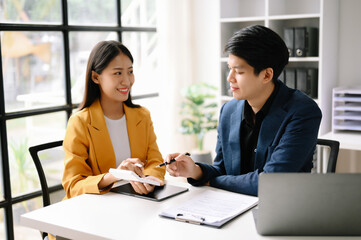 Two Asian business woman and man  discuss investment project working and planning strategy with tablet laptop computer in office.