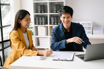 Two  Asian business  man and woman workers talking on the smartphone and using laptop Professionals in Teamwork  Finance, Marketing, and Success