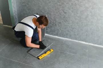 A male construction worker installs a large ceramic tile