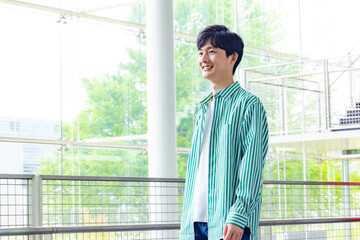 Casual Asian man smiling inside the building. University student.