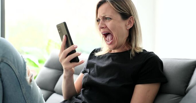 Woman learning bad news and screaming into mobile phone at home 4k movie slow motion. How to deliver bad news concept 