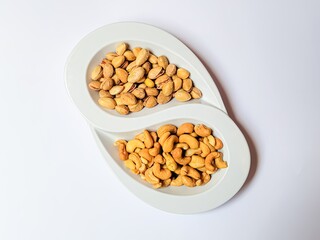 Compartmental dish with cashews and pistachios on white background.