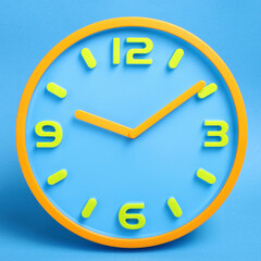 blue clock with yellow numbers and arrows on a blue background