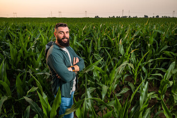Portrait of farmer who is cultivating corn. He is satisfied with good progress of plants....