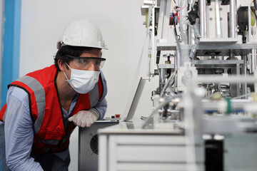 Fototapeta na wymiar Caucasian mechanic technician maintenance, repairing industrial machinery equipment in factory. Professional worker in protective clothing with computer and mask using wrench at manufacturing factory