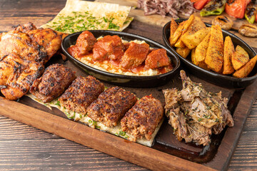 Mixed Turkish grill consisting of adana kebab, grilled chicken and lamb tandoori on wooden table