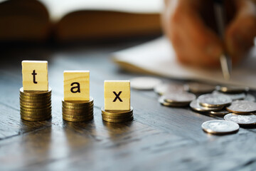 Tax Concept with wooden block on stacked coins