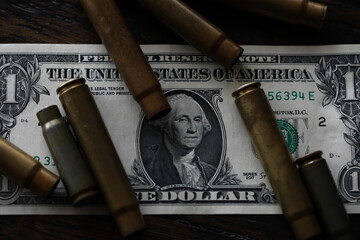 Illegal selling, criminal money concept, US dollars and bullet for a gun, cartridges on a background