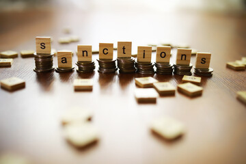 Word Sanctions made of wooden block letters with coins stacks