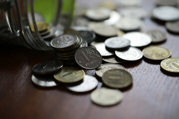 Russian rubles and metal coins inside a glass jar close-up on black blurred background