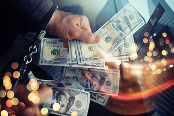  Double exposure city and hands of a man with handcuffs on a background of us dollars. Fraud, cyber...