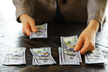 Female hands counting American one hundred dollar bills against the background of smaller bills of...
