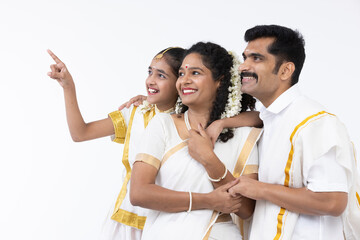 Smiling south indian parents and daughter posing in traditional clothing.