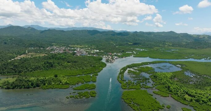 Aerial view of mangroves forest near city town. Blue sky and clouds. Mindanao, Philippines.