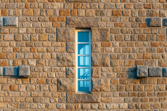 Old window on the wall. A window on the stone wall of a tower. Through it, you can see the mesh spiral staircase.