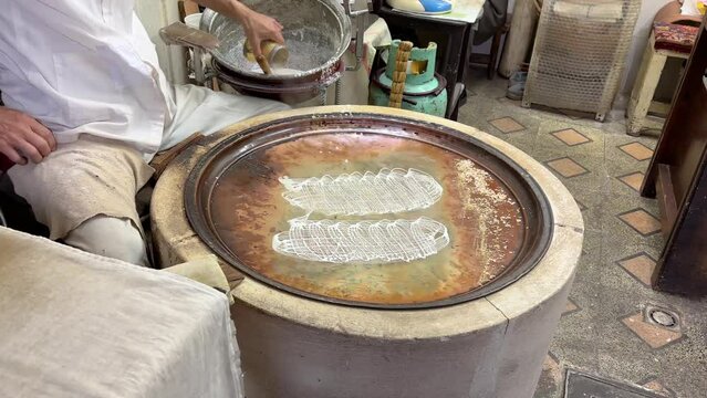 A local people pastry making workshop make rice liquid thread on a fry pan for sweet dessert with walnut and cinnamon roll confectionary product to sell in local market food cullinary cuisine ramadan