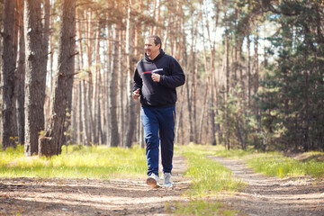 overweight man on a morning run in a sunny pine forest