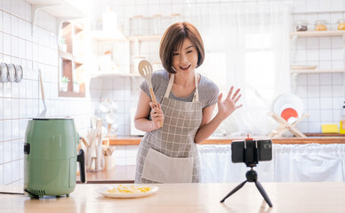Portrait of asian chef girl cooking potato fried by Air Fryer machine in kitchen home with live...