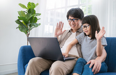 Portrait of asian man father and little daughter girl live online class vlog say hi on virtual computer virtual home office. Freelance online education sme happy man video call meet laptop at home