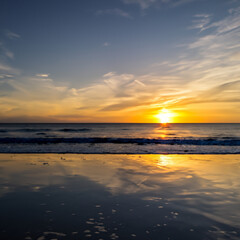Fototapeta na wymiar Sonnenuntergang am Strand mit Wolken mit Meer