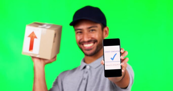 Asian man, box and phone on green screen for completed payment against a studio background. Portrait of male person or delivery guy show smartphone app in success for order transaction in ecommerce