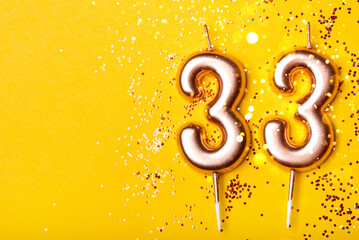 33 years celebration. Greeting banner. Gold candles in the form of number twenty eight on yellow...