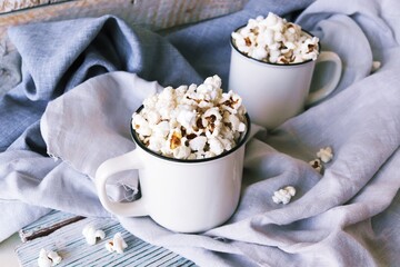 Two cups of delicious popcorn, on a linen cloth, on a wooden table