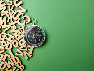 Closeup wooden letter and compass with a green background.