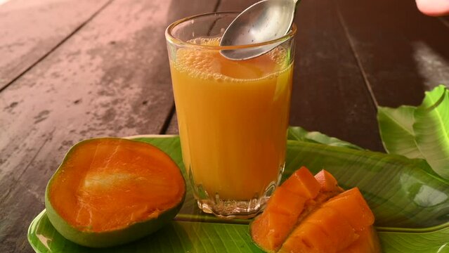 Mango juice with mango slice isolated on black background. Mango shake. Glass of  Fresh mango juice. This is a traditional and most popular drink of Indian in summer. Slow motion video.
